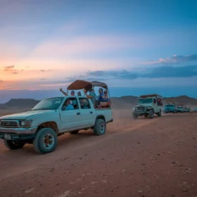 Autos fahren durch die Wüste bei Sonnenuntergang.