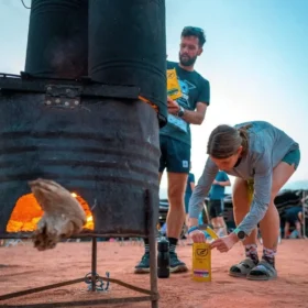Zwei Personen kochen über Feuer